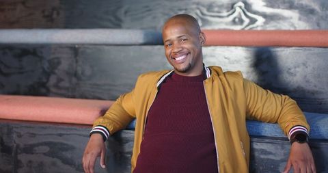 African american man smiling and relaxing on tiered bench in modern minimalist lounge
