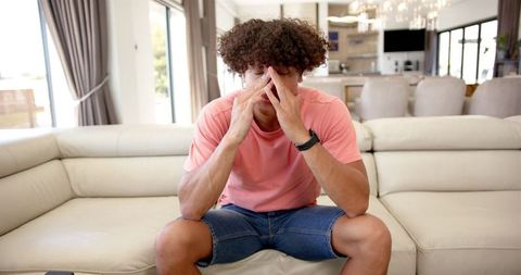 Young man feeling stressed at home on sofa