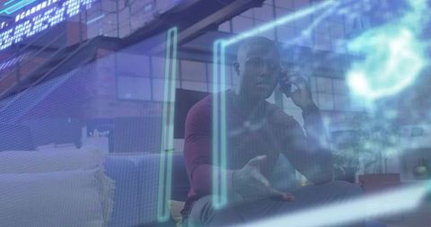 Man talking on phone and gesturing on sofa with holographic interface in office lounge