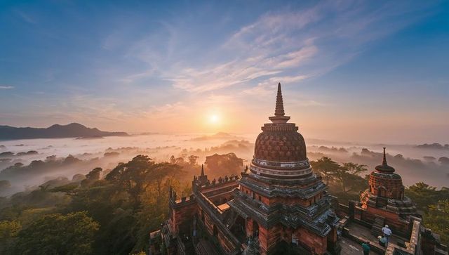 Ancient pagoda glowing in sunrise mist over jungle temple complex