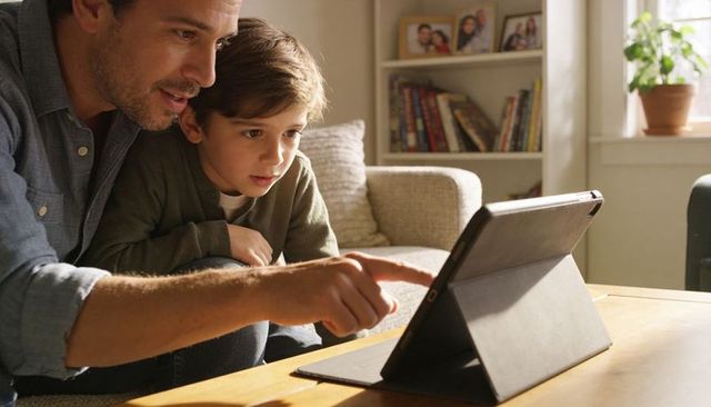 Father and Son Exploring Tablet Together on Couch Bonding Over Digital Learning and Play