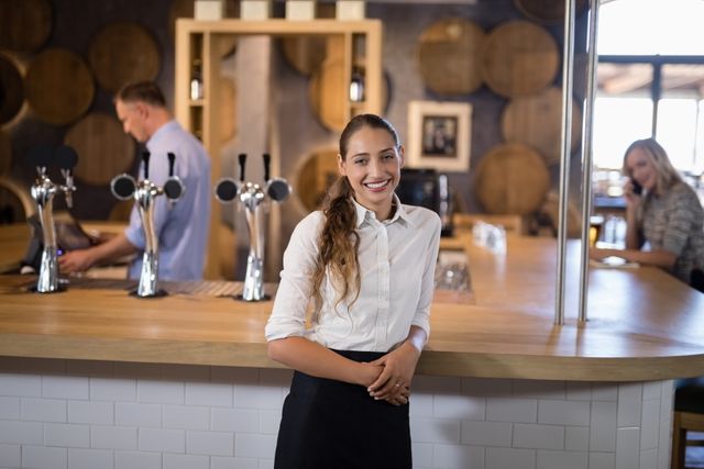 Portrait of smiling female bartender standing near bar counter