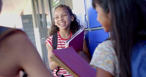 Joyful Schoolgirls Having a Friendly Conversation in Hallway