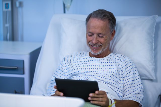 Sick patient sitting on bed and using digital tablet in hospital