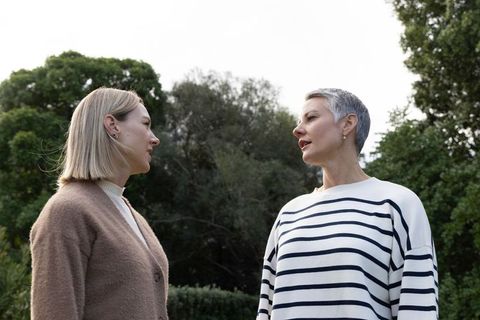 Women talking outdoors in park wearing cardigan and striped top