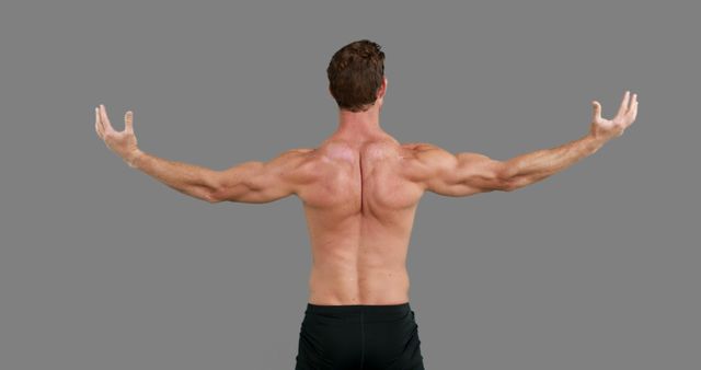 A Caucasian man is showcasing his muscular back and arms in a pose that highlights his physique, with copy space. His stance exudes strength and fitness, ideal for content related to health, exercise, and bodybuilding.