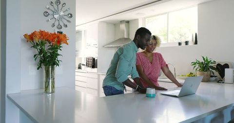 Couple Smiling Using Laptop Together in Modern Kitchen