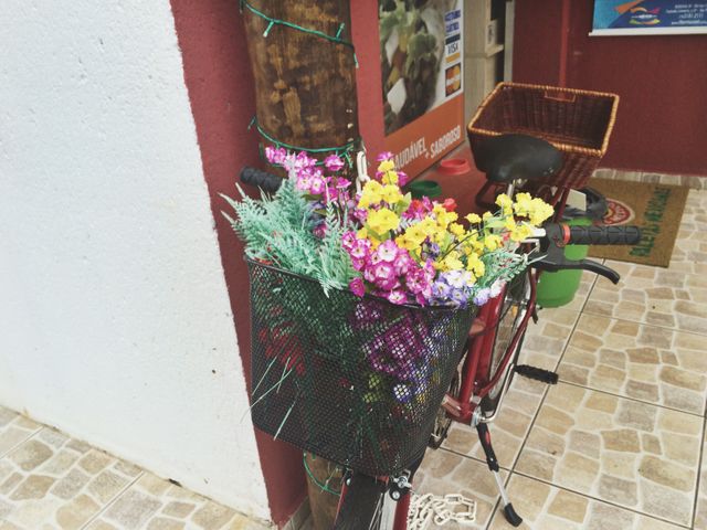 Bicycle parked on a tiled patio with a basket filled with colorful flowers like daisies and greenery gives a quaint and charming feel. Suitable for topics like outdoor decor, summer activities, vintage charm, and business promotions for florists or garden shops.