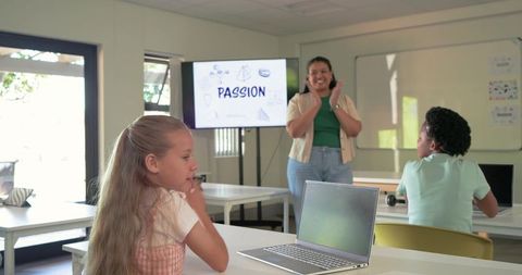 Diverse teacher leading engaged students, laptop open, PASSION on screen in classroom