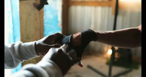 Male Boxing Trainer Wrapping Fighter's Hands for Gym Training