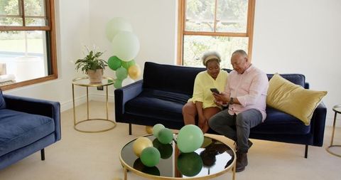 Seniors Chatting in Relaxed Celebration Living Room with Balloons