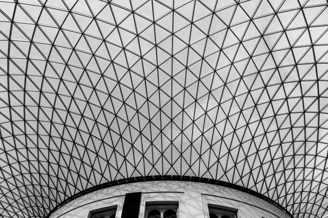 Black and white image of modern architectural dome with intersecting geometric patterns. Ideal for use in architectural design presentations, contemporary design inspiration boards, or educational materials focusing on structural engineering and architectural styles.