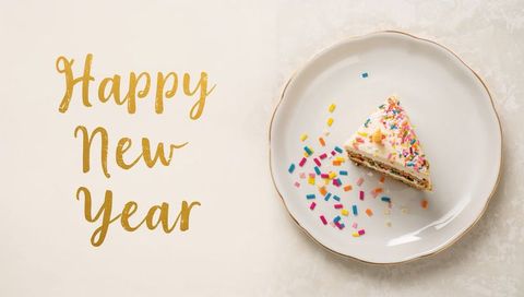 Festive triangular cake slice with gold happy new year script and colorful sprinkles