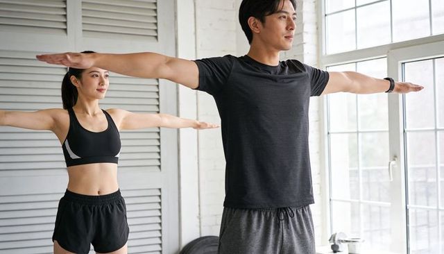 Couple stretching in sunlit studio improving balance and posture wearing fitness tracker