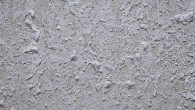 Peeling white plaster texture revealing beige underlay and fibrous stucco detail