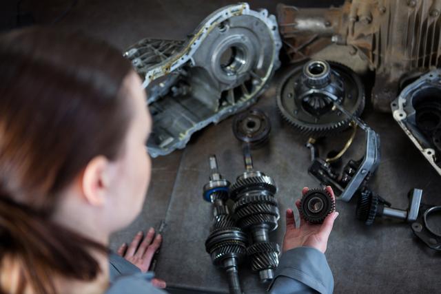 Female mechanic holding spare parts of car at repair garage
