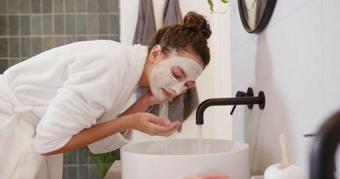 Woman projecting serenity while washing face in stylish minimalist bathroom
