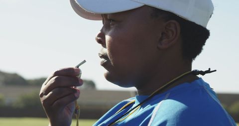 Focused coach blowing whistle on rugby field
