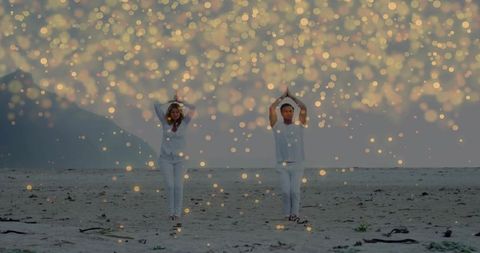 Couple Walking Beach Raising Arms into Triangle Yoga Pose at Dawn with Golden Bokeh Glow