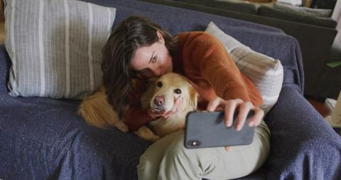 Woman Snuggling Golden Retriever Taking Selfie on Couch