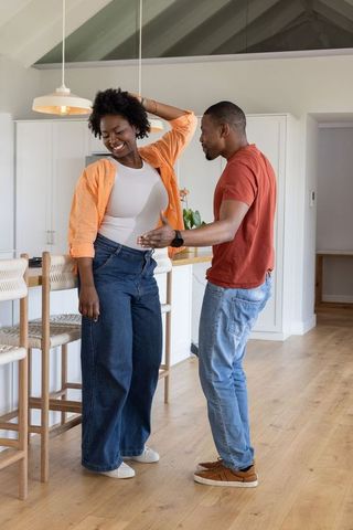 African american couple dancing and laughing in bright modern kitchen