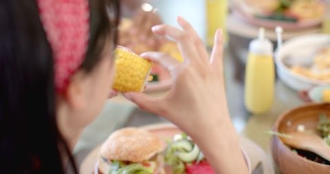 Young Woman Eating Corn at Casual Meal Gathering Indoors - Download Free Stock Images Pikwizard.com