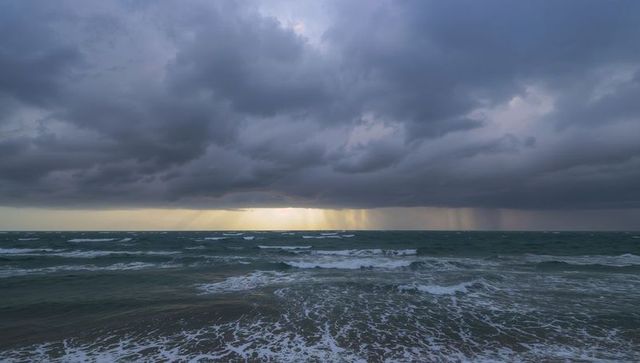 Majestic seascape at stormy sunrise with sunbeams and rolling waves