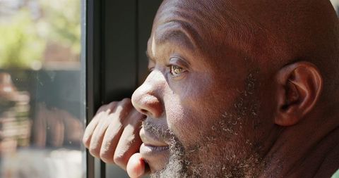 Mature man contemplating life while looking out window