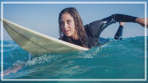 Caucasian woman paddling on surfboard in clear ocean waters