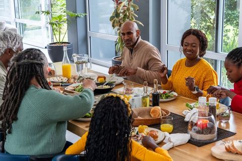 Multigenerational african american family sharing home-cooked meal around sunlit dining table