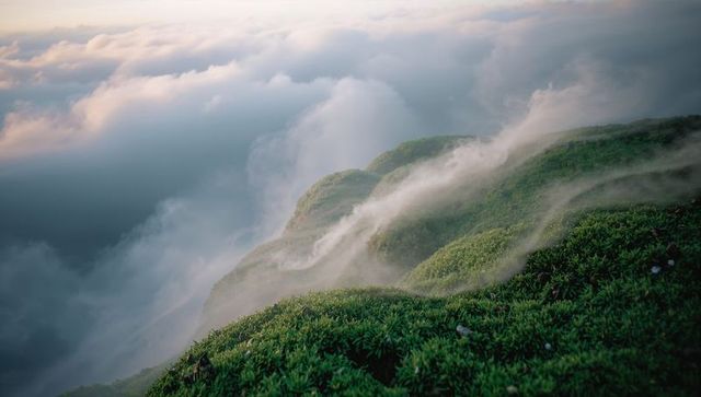 Mountain ridge emerging in morning mist at sunrise