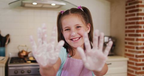 Smiling girl in kitchen covered with flour