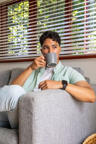 Young Man Relaxing on Sofa With Coffee Mug and Smartwatch