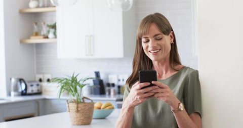 woman texting in modern kitchen with natural lighting - Download Free Stock Images Pikwizard.com