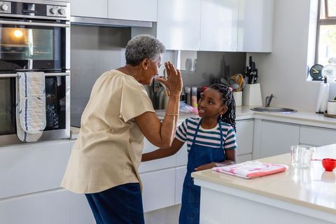 Senior african grandmother and granddaughter baking together in bright modern kitchen