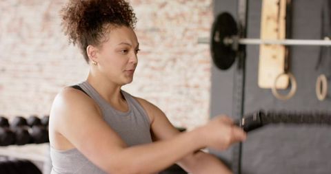 Woman powering through battle rope workout in urban brick gym for strength training