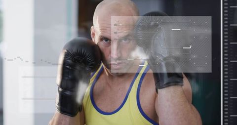 Boxer standing in guard wearing yellow tank top with black gloves and digital hud overlay