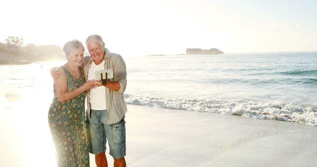 A joyful elderly couple taking a selfie together on a serene beach at sunset. The warm, golden light reflects off the ocean, creating a peaceful and romantic atmosphere. Ideal for use in marketing materials for travel agencies, retirement communities, or health and wellness products geared towards seniors.