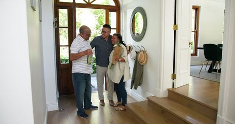 Welcoming Senior Friends at Entrance with Wine and Flowers