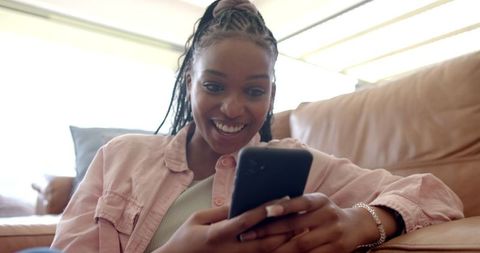 Joyful African American Woman Using Smartphone on Couch