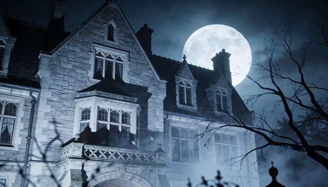 Moonlit gothic mansion looming under full moon with fog and bare creeping tree silhouettes