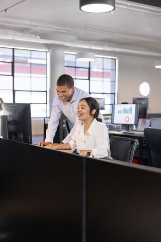 Diverse Coworkers Collaborating on Bar Chart in Modern Office