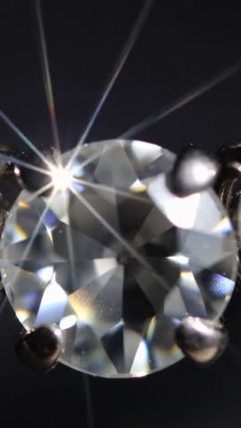 Vertical macro video capturing sparkling diamond with shifting focus, starburst and prong detail