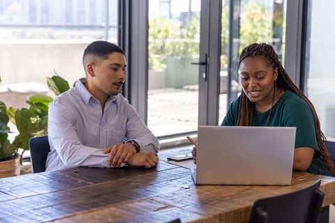 Diverse Coworkers Collaborating at Office Table with Laptop