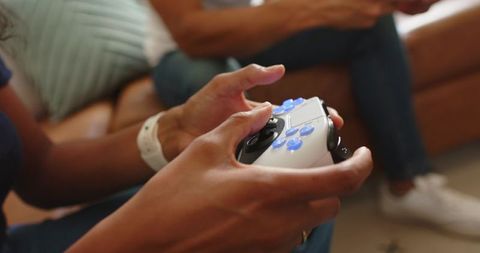 African american couple holding wireless controller playing video games on leather couch