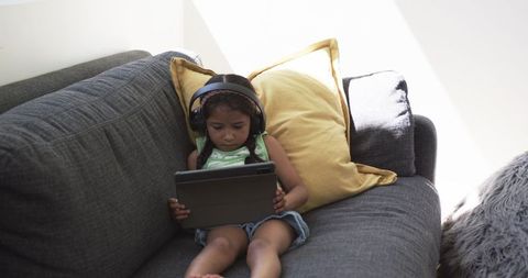 Child Engaged with Tablet on Cozy Gray Couch