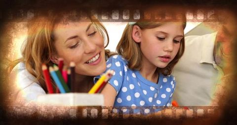 Mother guiding daughter drawing with colored pencils at tabletop, warm vintage film frame