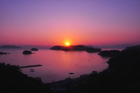 Sunset Over Island-Dotted Bay with Pink Purple Sky, Reflective Water, Serene Coastal Vista