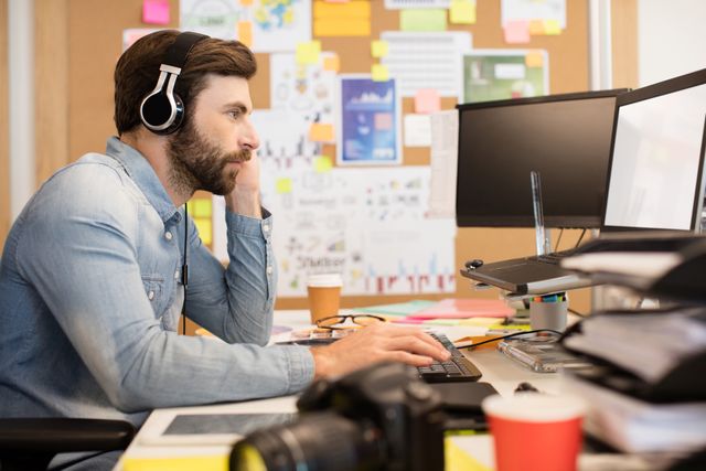 Side view of businessman wearing headphones while working in creative office
