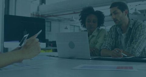 Collaborating team reviewing charts on laptop in open-plan coworking industrial workspace